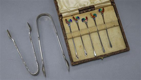 Five silver and enamel cocktail sticks and two pairs of silver sugar tongs.